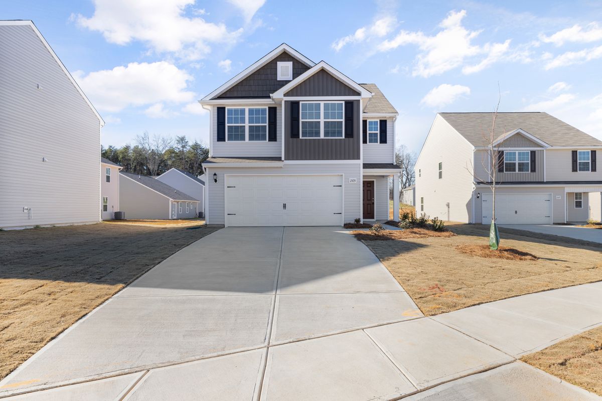 Newly poured plain concrete driveway leading to a two-storey home