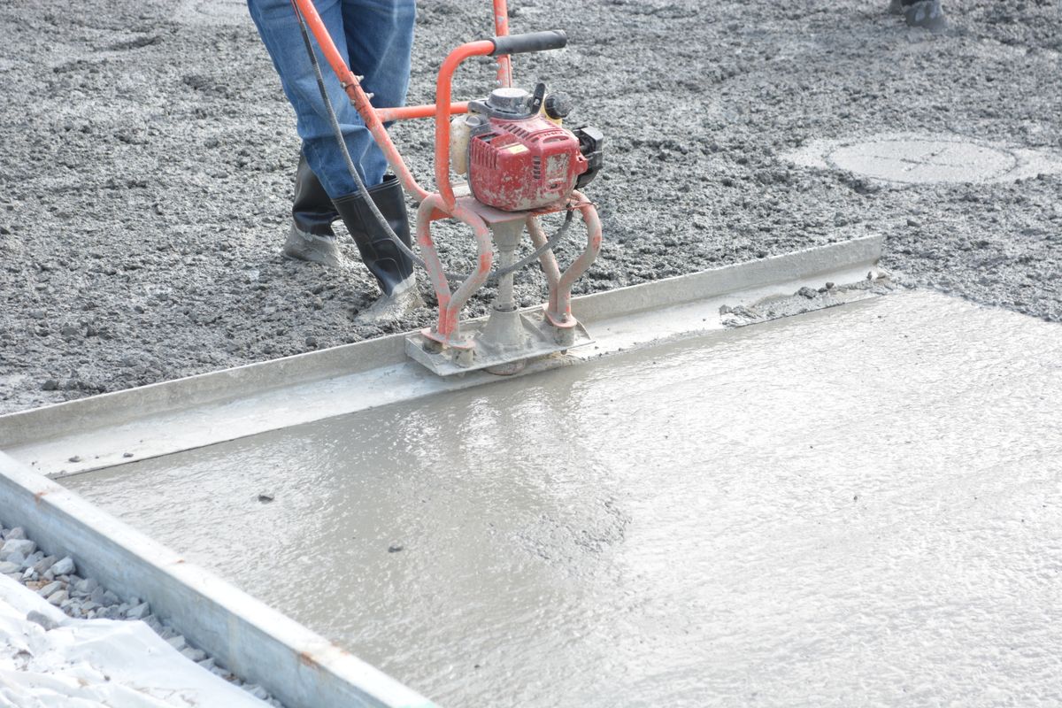 Concreter running a power screed across a freshly poured concrete slab in formwork